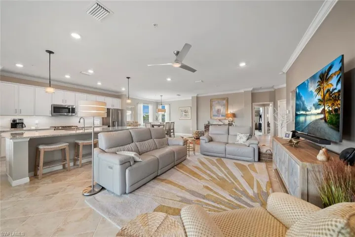 Living room with ornamental molding, light tile patterned flooring, sink, and ceiling fan