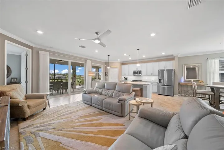 Living room featuring crown molding, a healthy amount of sunlight, ceiling fan, and light tile patterned floors