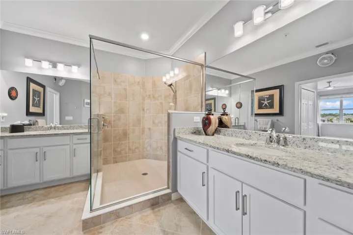 Bathroom with ceiling fan, a shower with door, vanity, crown molding, and tile patterned flooring