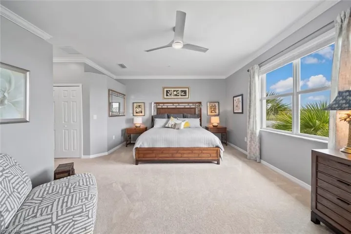 Carpeted bedroom with ornamental molding and ceiling fan