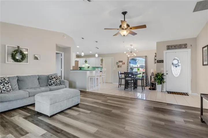 Living room with a chandelier, ceiling fan, and light wood-style floors