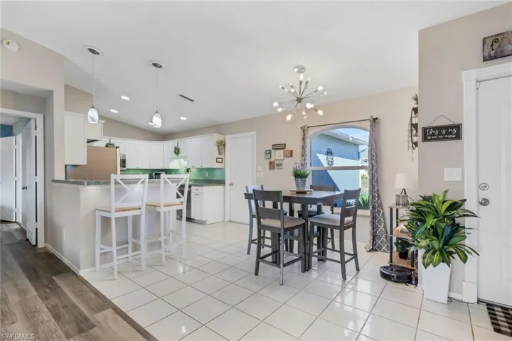 Dining area featuring lofted ceiling, light tile patterned floors, and suspended lighting
