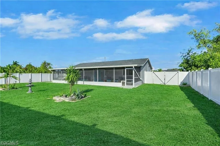 Rear view of house with a fenced backyard, a gate, and a sunroom
