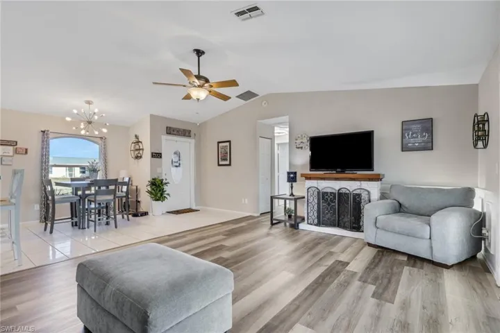 Living room featuring light wood finished floors, a ceiling fan, and hanging lights
