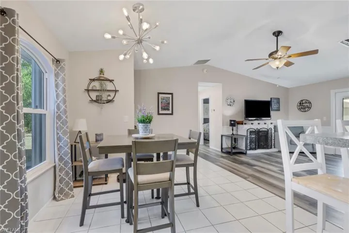 Dining space with a ceiling fan, light tile patterned floors, suspended lighting, and lofted ceiling