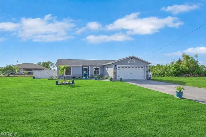 Single story home featuring concrete driveway, a front lawn, a garage, and stucco siding
