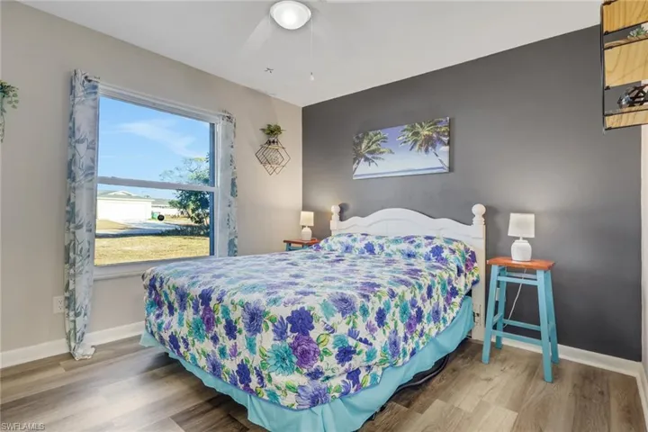 Bedroom featuring wood finished floors, an accent wall, and a ceiling fan