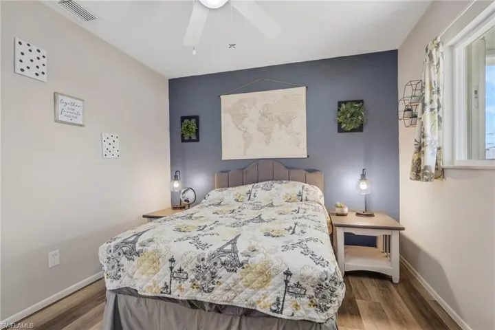 Bedroom featuring an accent wall, dark wood-style flooring, and a ceiling fan