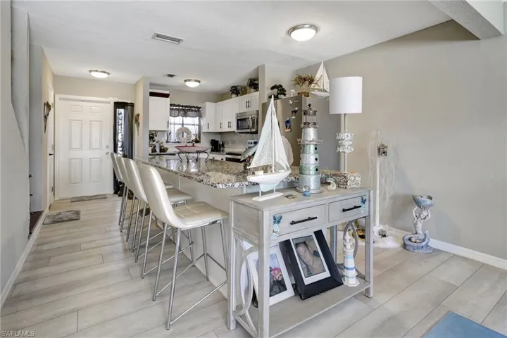 Kitchen with range, white cabinetry, light hardwood / wood-style floors, and light stone countertops