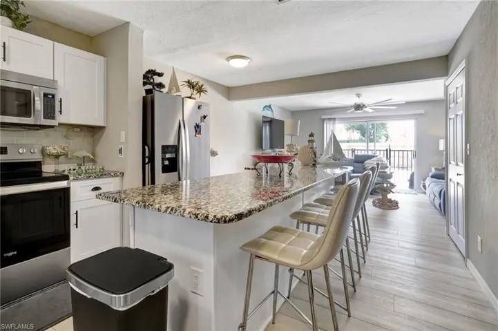 Kitchen with light hardwood / wood-style floors, white cabinets, ceiling fan, and stainless steel appliances