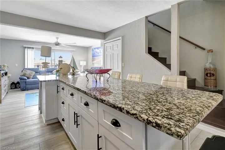 Kitchen featuring white cabinetry, light wood-type flooring, ceiling fan, and a breakfast bar area