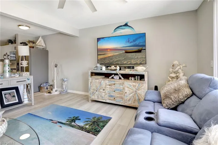 Living room featuring beamed ceiling, light wood-type flooring, and ceiling fan