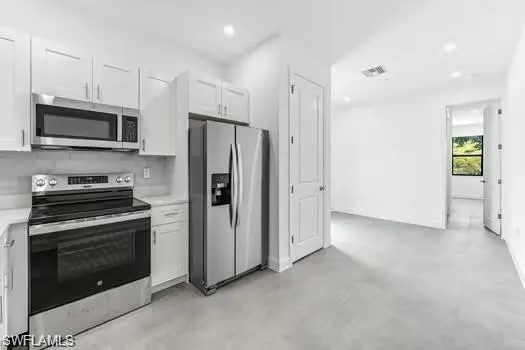 Kitchen #2 in Second Unit featuring stainless steel appliances, light countertops, concrete floors, white cabinetry, and recessed lighting