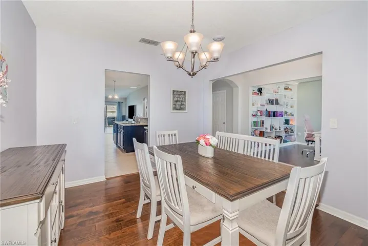 Dining area featuring visible vents, a notable chandelier, arched walkways, and dark wood-type flooring