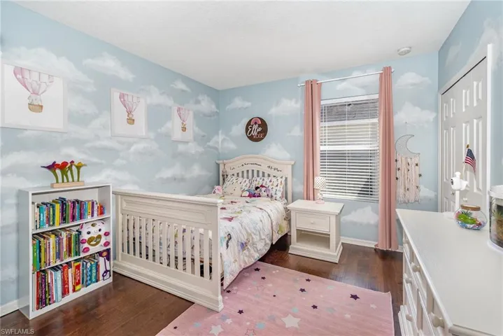 Bedroom with baseboards, wallpapered walls, a closet, and wood finished floors