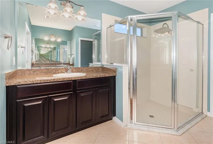 Bathroom with an inviting chandelier, tile patterned floors, and a shower stall