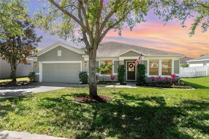 Ranch-style home featuring fence, a garage, concrete driveway, a front yard, and stucco siding