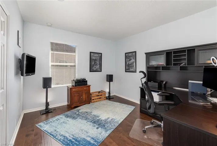 Office with dark wood-type flooring and baseboards
