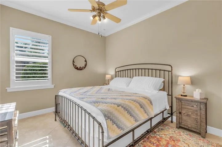 Tiled bedroom with ceiling fan and crown molding