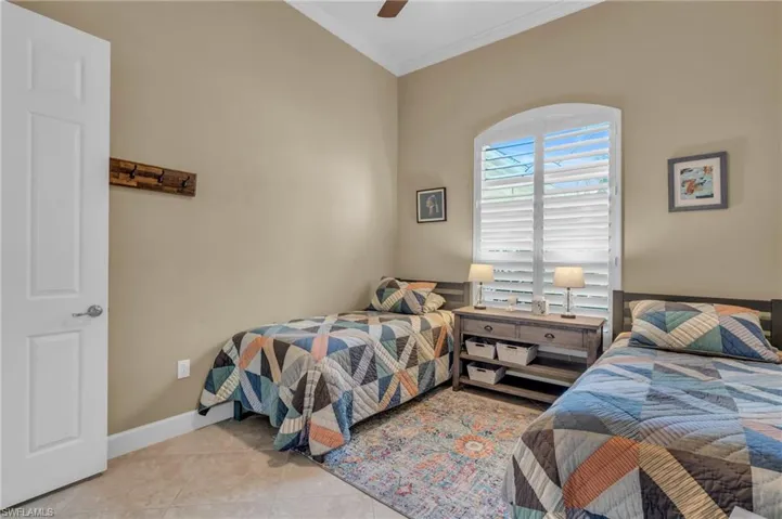 Tiled bedroom with ceiling fan and crown molding