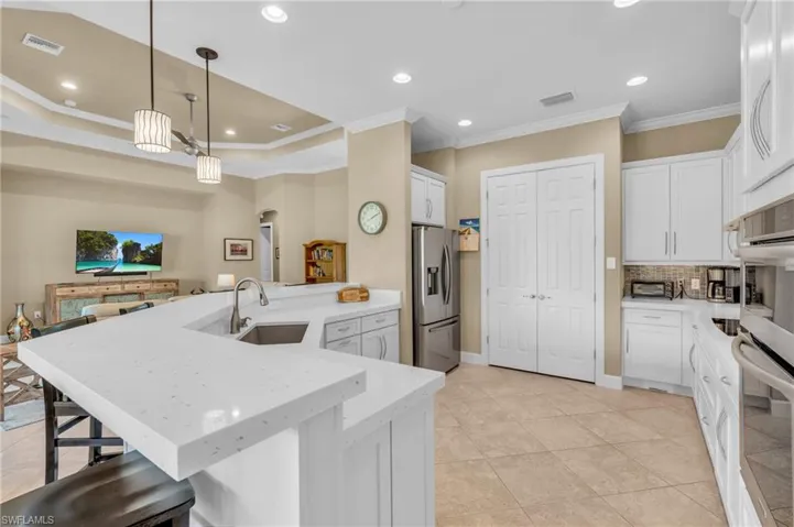 Kitchen featuring ornamental molding, stainless steel appliances, sink, decorative light fixtures, pantry and white cabinetry