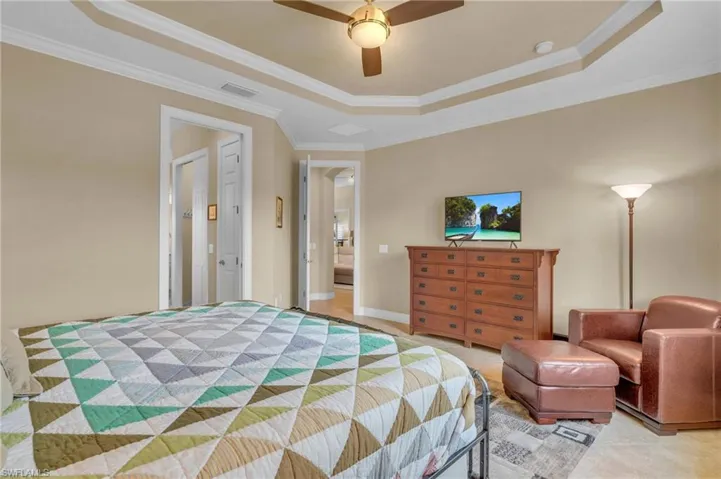 Bedroom with ceiling fan, ornamental molding, and a tray ceiling