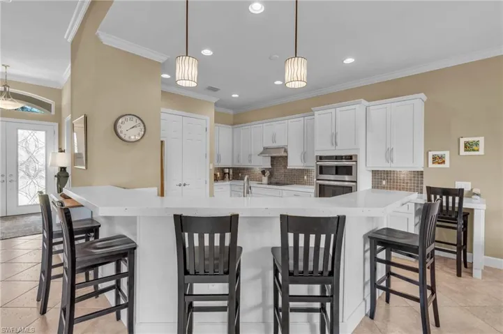 Kitchen featuring a french door pantry, decorative light fixtures, white cabinetry, and ornamental molding