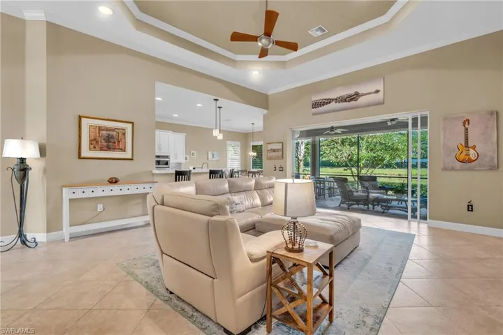 Living room with ceiling fan, crown molding, a towering ceiling, a tray ceiling, and light tile patterned flooring