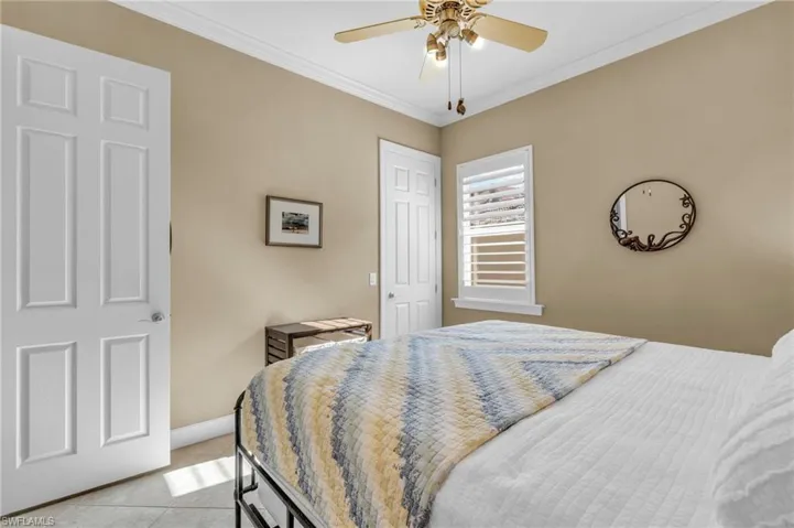 Bedroom featuring light tile patterned floors, ceiling fan, and crown molding