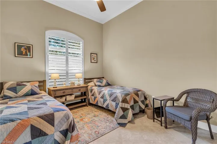 Tiled bedroom with ceiling fan and ornamental molding