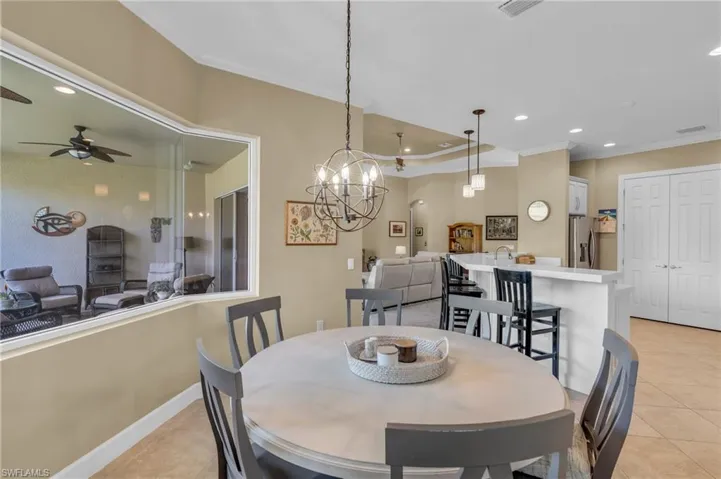 Tiled dining space with ceiling fan with notable chandelier and ornamental molding