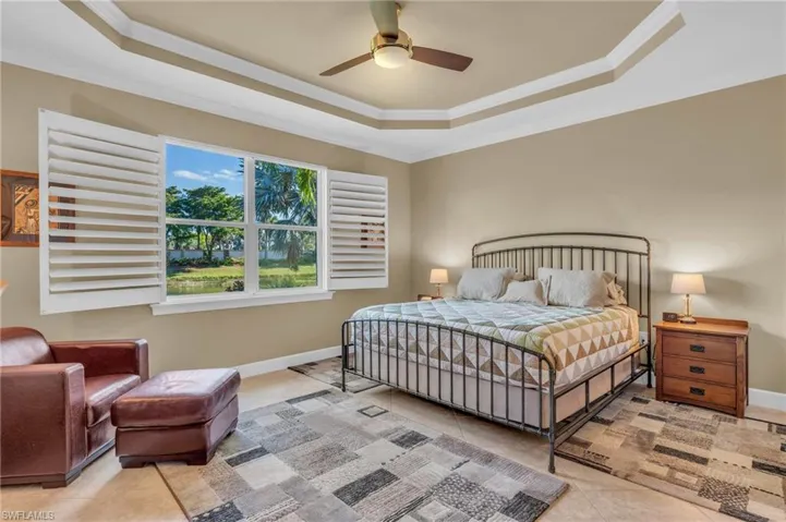 Bedroom with ceiling fan, a raised ceiling, light tile patterned floors, and crown molding