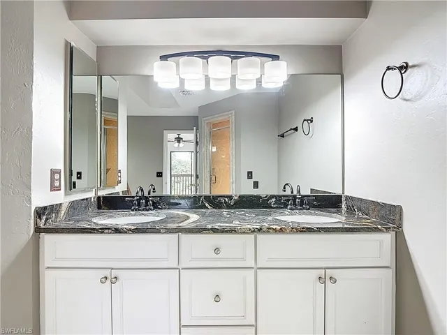 Full bath featuring a textured wall, double vanity, and ceiling fan
