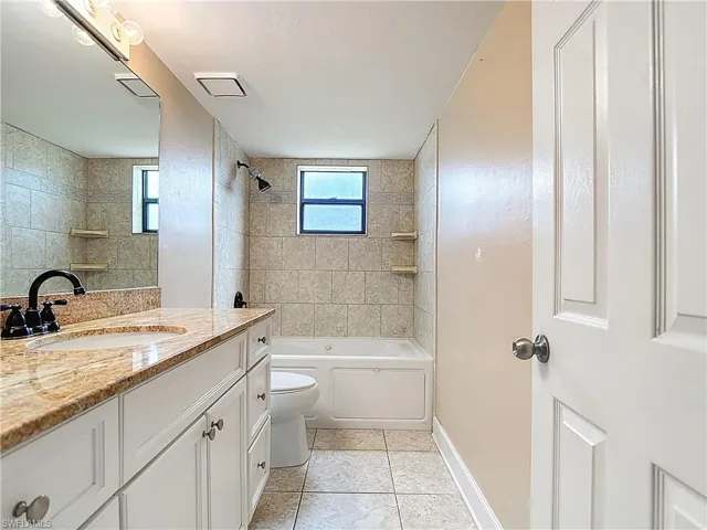 Full bathroom featuring vanity, shower / bath combination, healthy amount of natural light, and light tile patterned floors