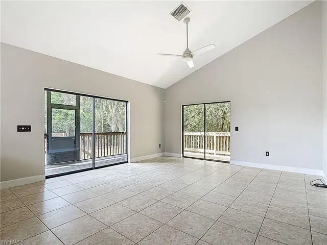 Spare room featuring high vaulted ceiling, ceiling fan, and light tile patterned flooring