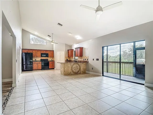 Kitchen featuring ceiling fan, backsplash, light tile patterned floors, high vaulted ceiling, and open floor plan