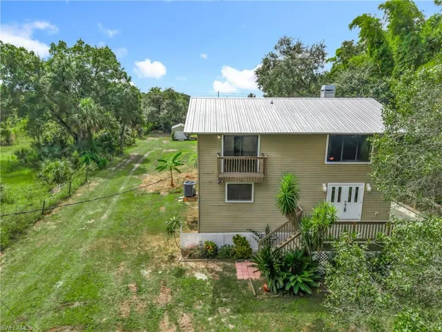 Rear view of property featuring a lawn, a metal roof, and a balcony