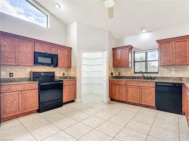 Kitchen featuring decorative backsplash, black appliances, and brown cabinets