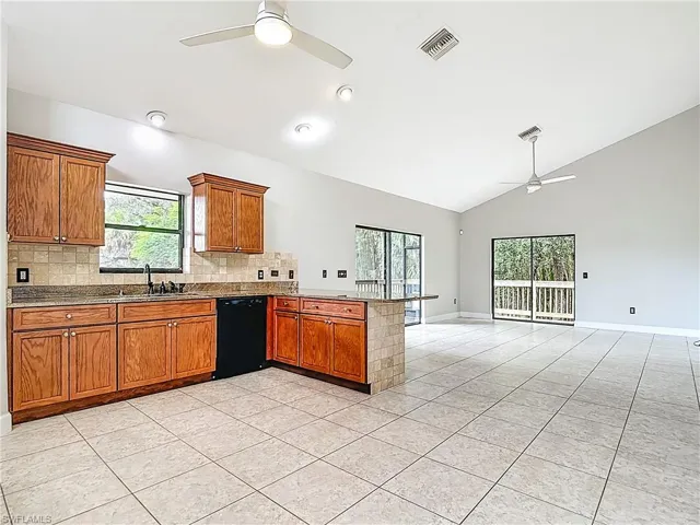 Kitchen with ceiling fan, brown cabinetry, a peninsula, tasteful backsplash, and light tile patterned floors