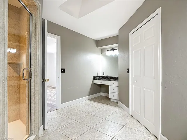 Full bath featuring vanity, a shower stall, and light tile patterned flooring
