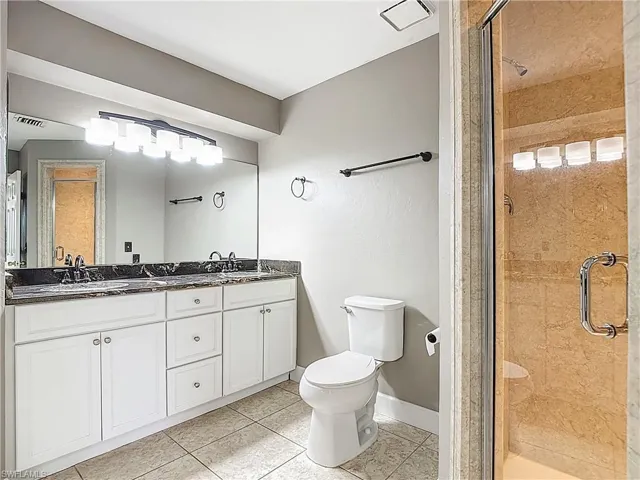 Bathroom featuring a stall shower, light tile patterned flooring, and double vanity