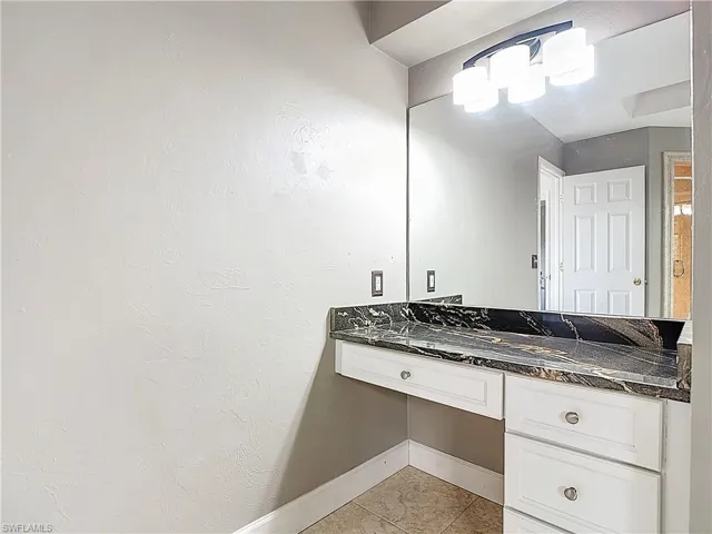 Bathroom featuring vanity, light tile patterned flooring, and a textured wall