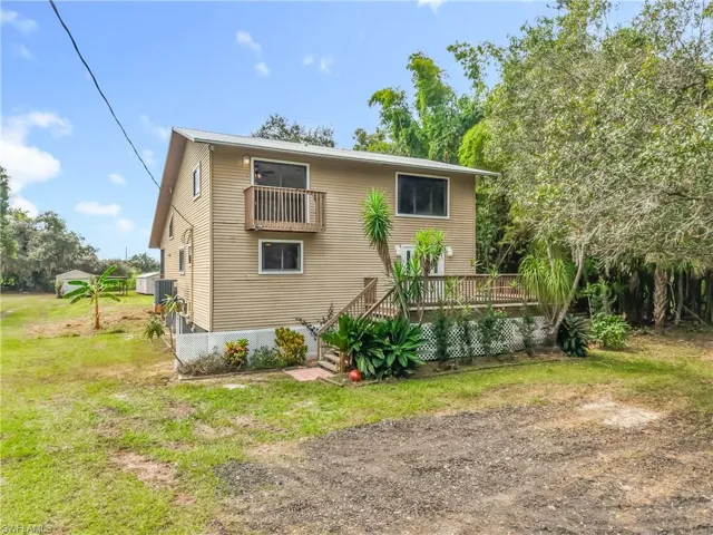 Rear view of house featuring a yard and stairway