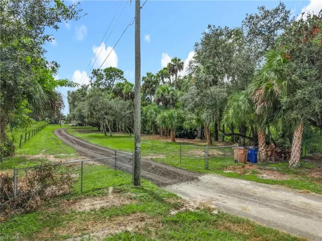 View of community with a gate, view of wooded area, and driveway
