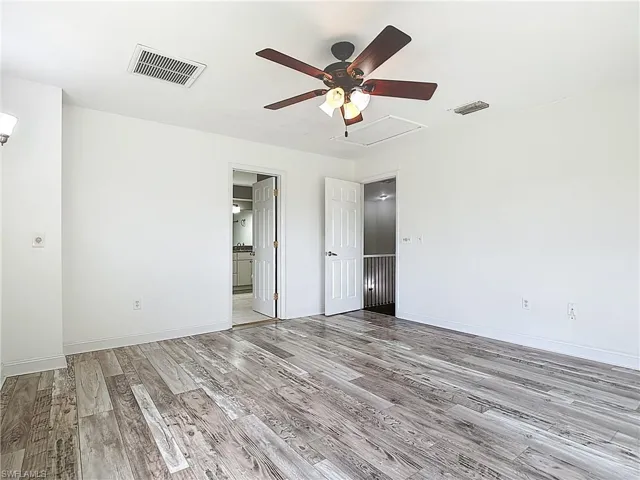 Unfurnished bedroom featuring light wood finished floors, ceiling fan, and ensuite bathroom