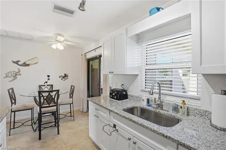 Kitchen featuring light stone countertops, white cabinetry, ceiling fan, and light tile patterned flooring