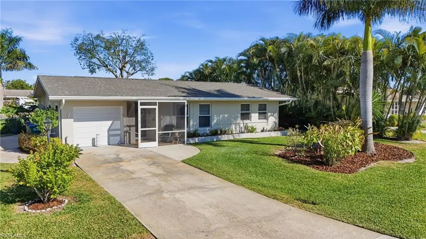 Ranch-style house featuring a sunroom, a garage, driveway, a front lawn, and roof with shingles