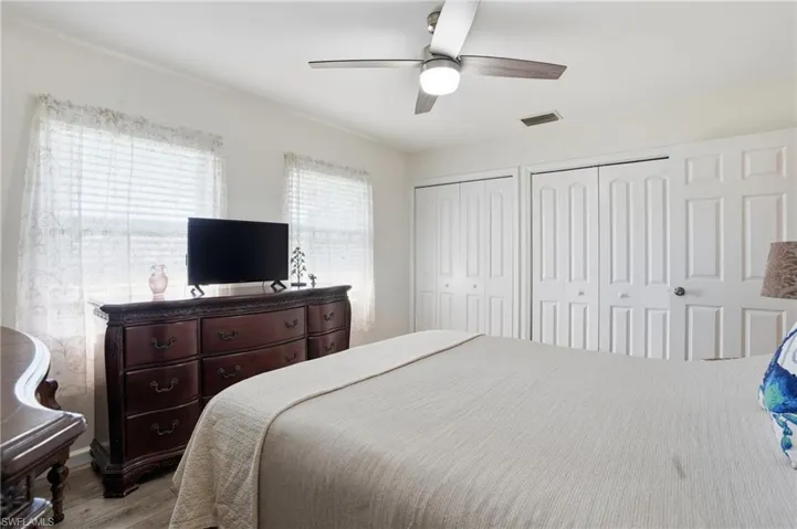 Bedroom with two closets, wood finished floors, and a ceiling fan