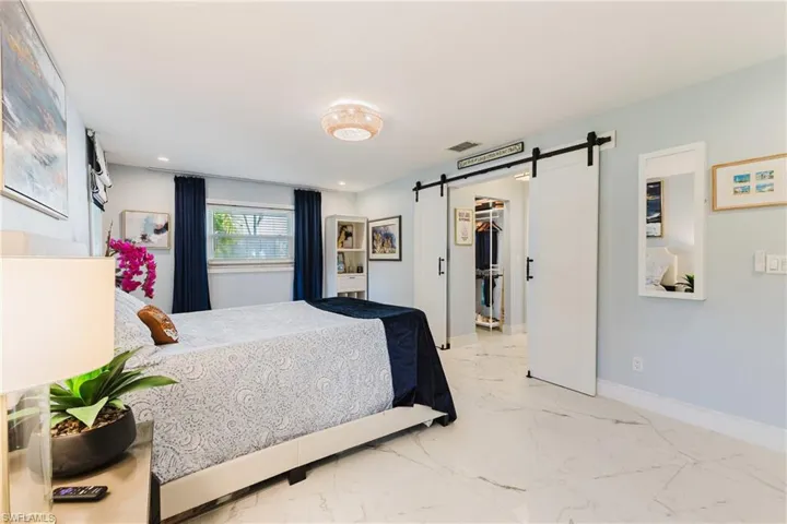 White marble-look tile flooring throughout, featuring a recessed ceiling light and a contemporary chandelier