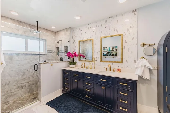 Dual vanity with dark blue cabinetry and gold hardware, featuring two undermount sinks and white countertops